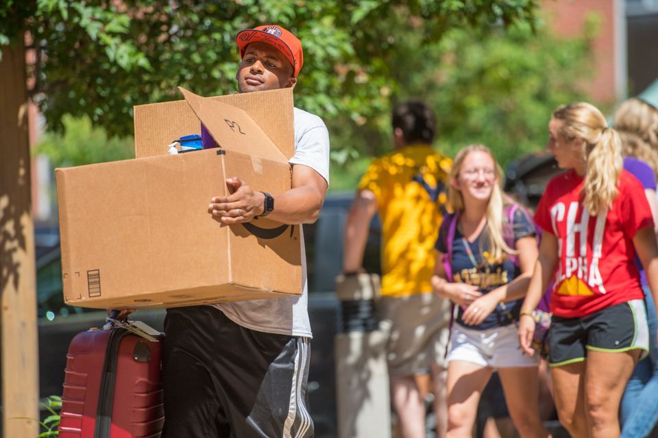 student carrying a box during move in