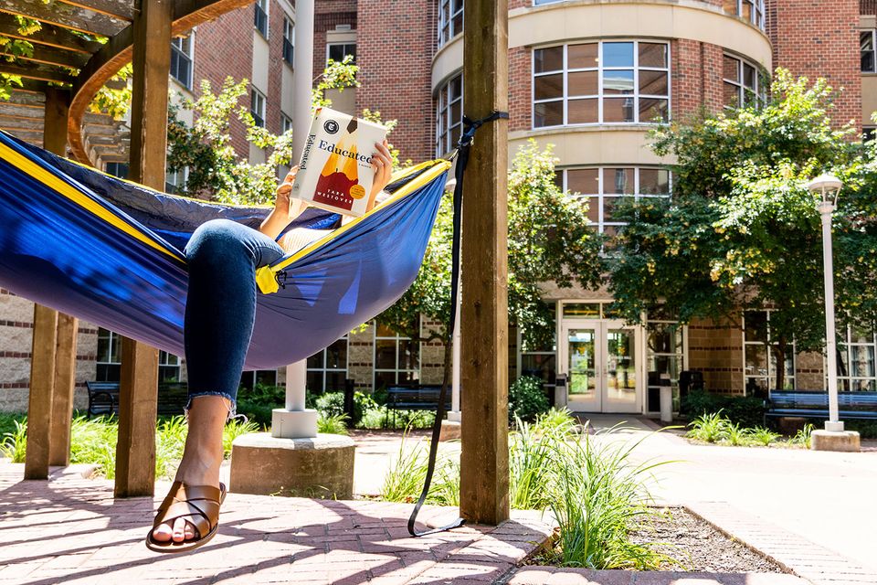 student in hammock in front of residence hall